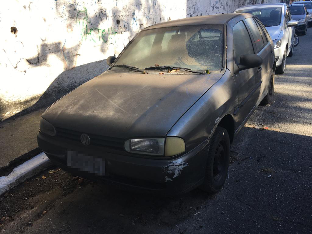 Frente de um carro preto abandonado na rua 